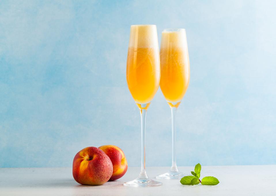 two glasses of champagne with a cocktail of Bellini and fresh peaches on a blue background. summer refreshing drink