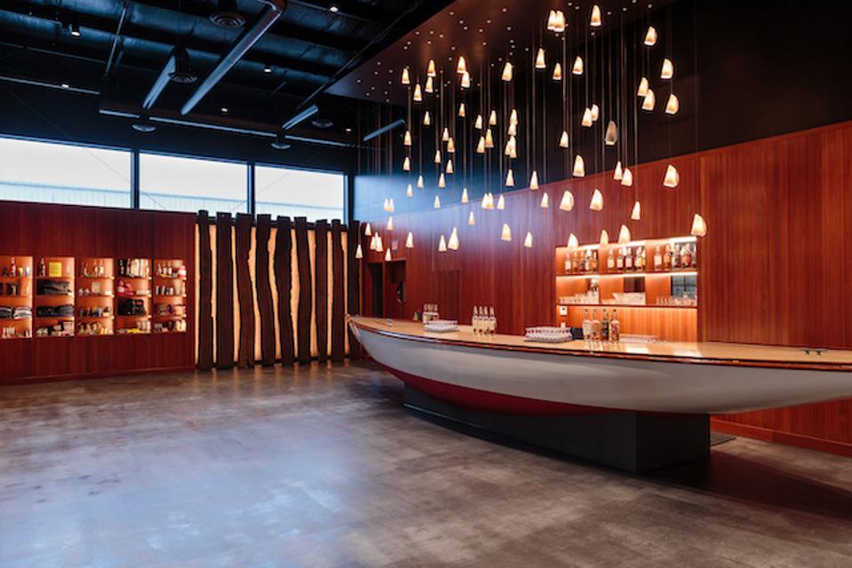 a room with a polished sail boat in the middle serving as a bar.