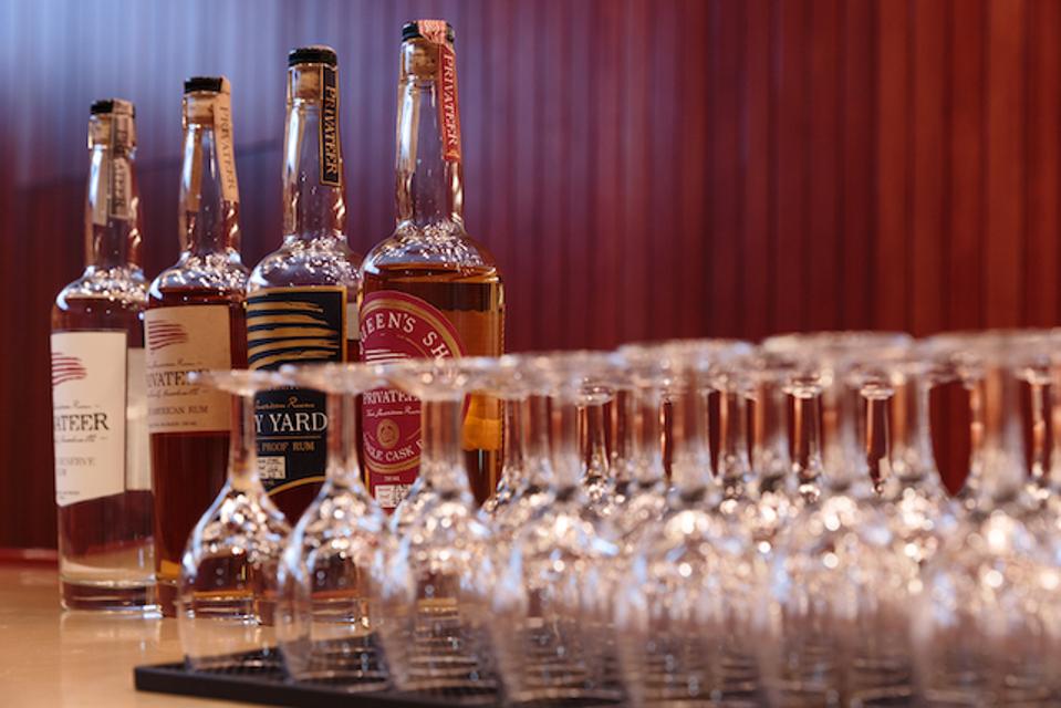 Bottles of Privateer rum on a bar with some tasting glasses.