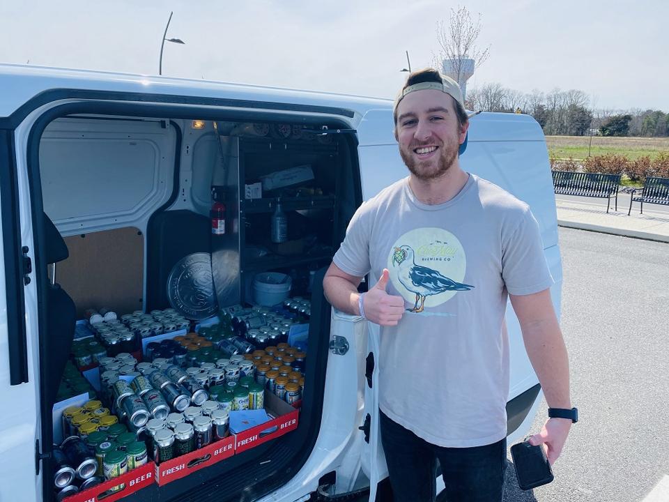 A man stands outside a van full of beer cans.