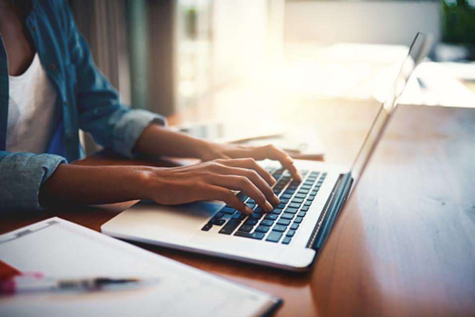 Individual typing on a laptop