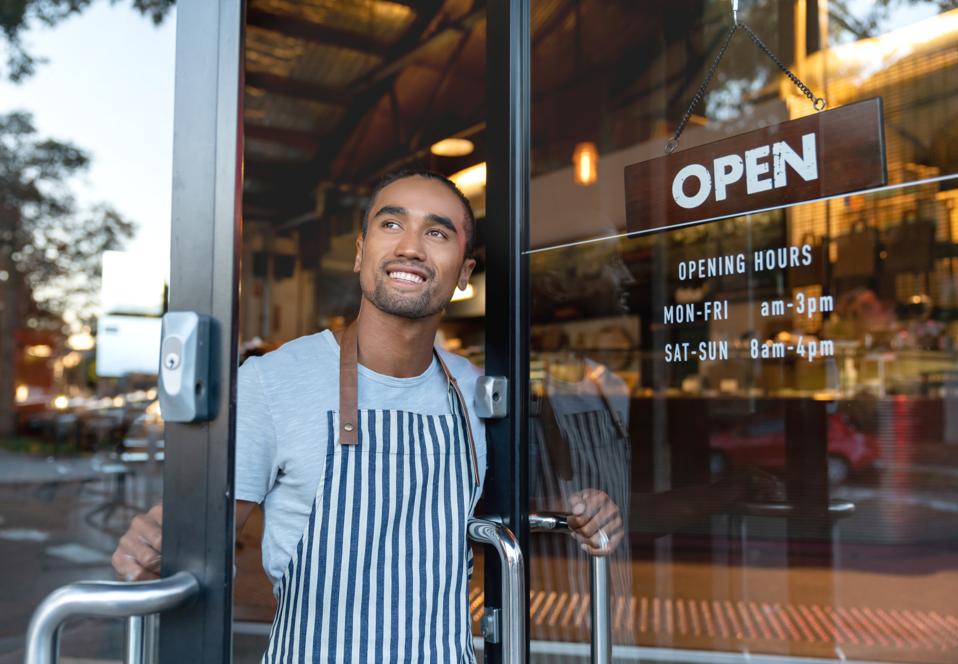 Happy waiter opening on the doors at a cafe