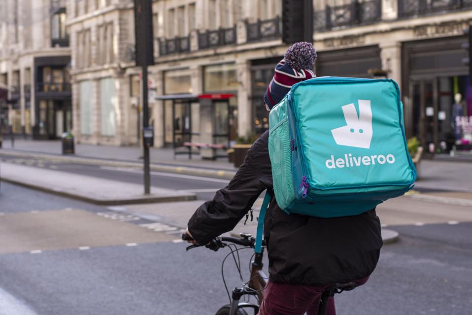 Deliveroo courier rides along the Regent Street delivering...