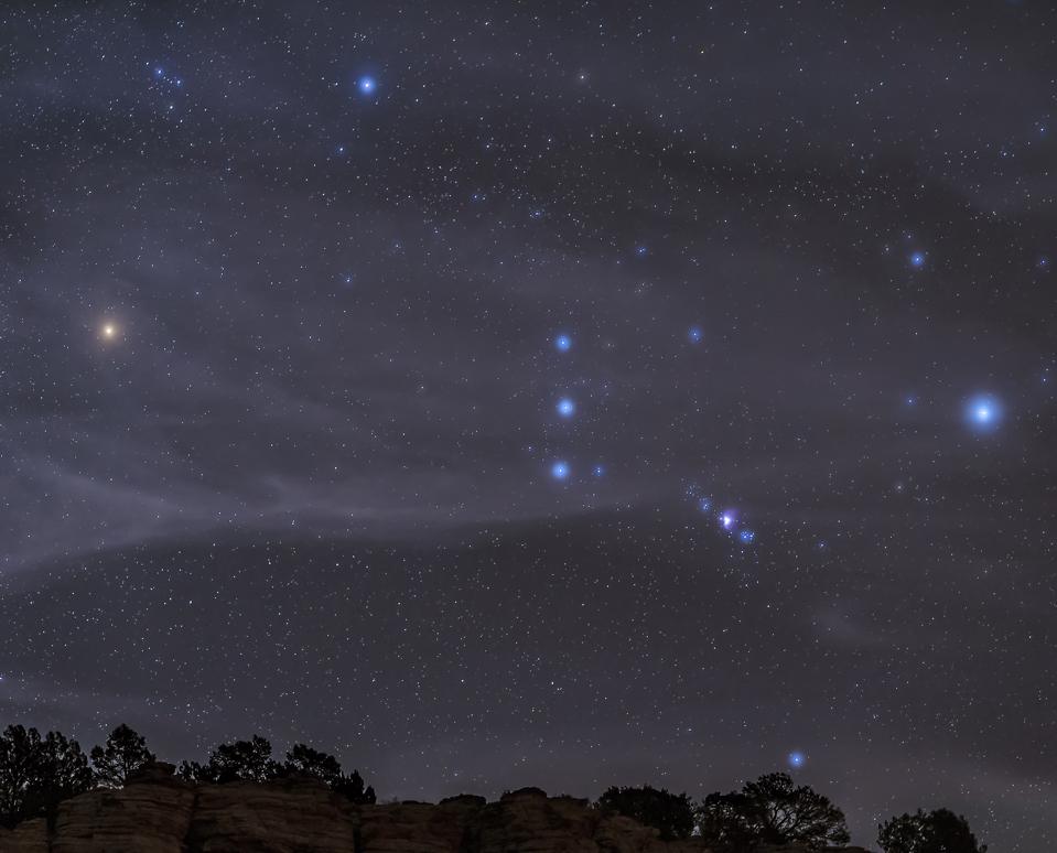 The Orion constellation rises over a hill through high thin clouds near Black Mesa, Oklahoma.