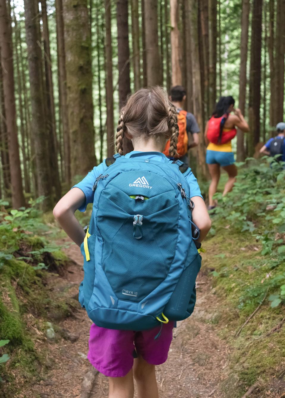 Girl with backpack hiking in the woods