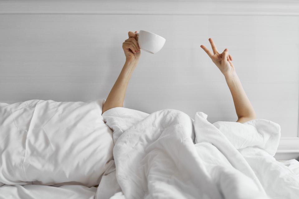 Woman with a mug of coffee in bed