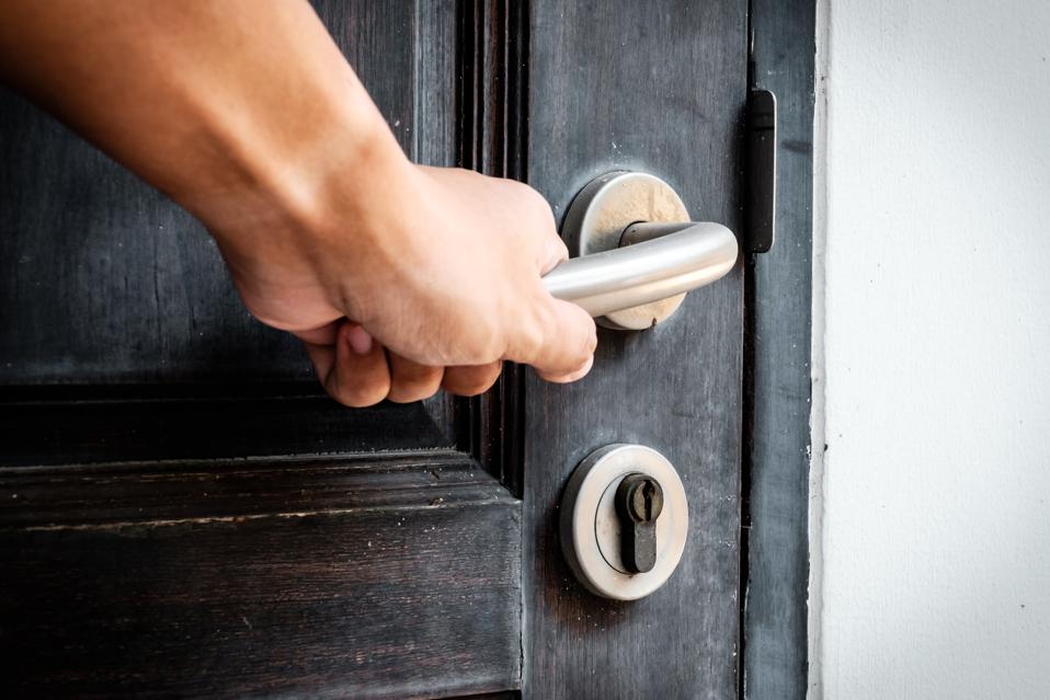 Hand opening a wooden door