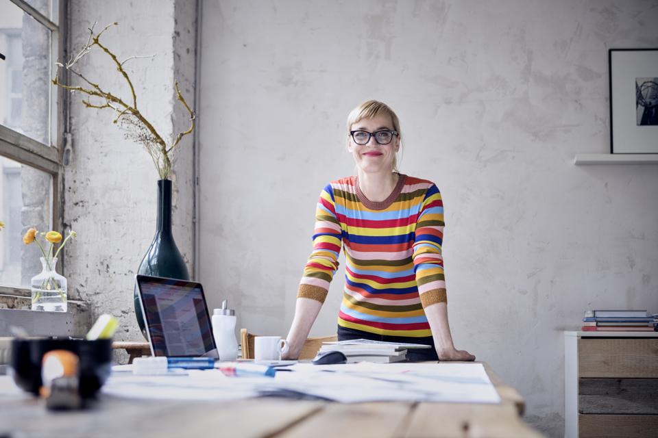Portrait of smiling woman at desk in a loft