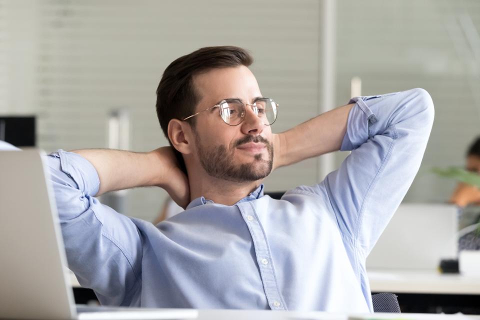 Relaxed businessman taking break holding hands behind head enjoying rest