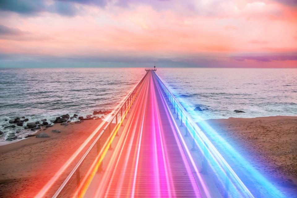 Creative composition of colorful lights trails in motion over the sea.