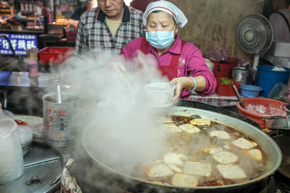 A woman selling spicy ″stinky tofu″ (fermented beancurd)...