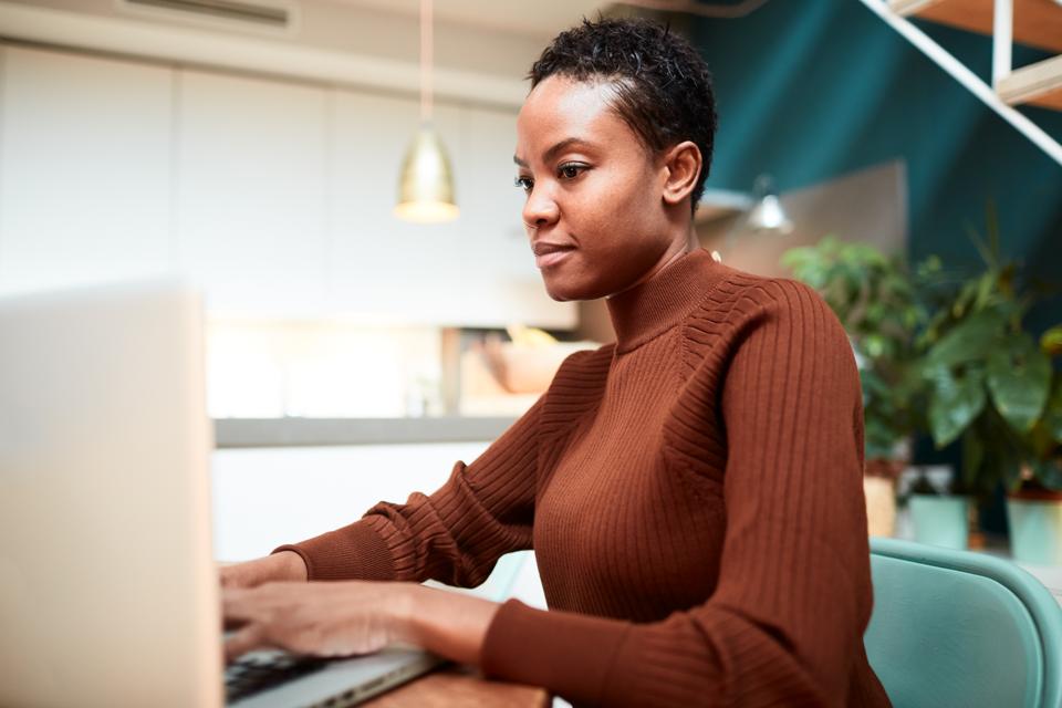 Woman working from home, typing on a laptop.