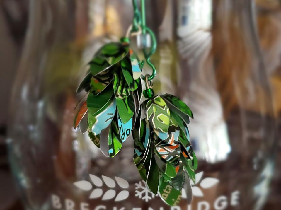 a pair of earrings made from scraps of beer cans