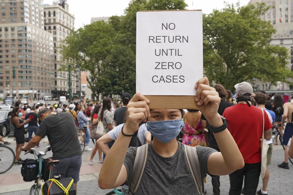 A protester holds a placard that says No return until zero...