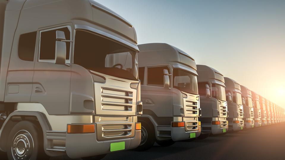 Row of cargo electric trucks against with sun