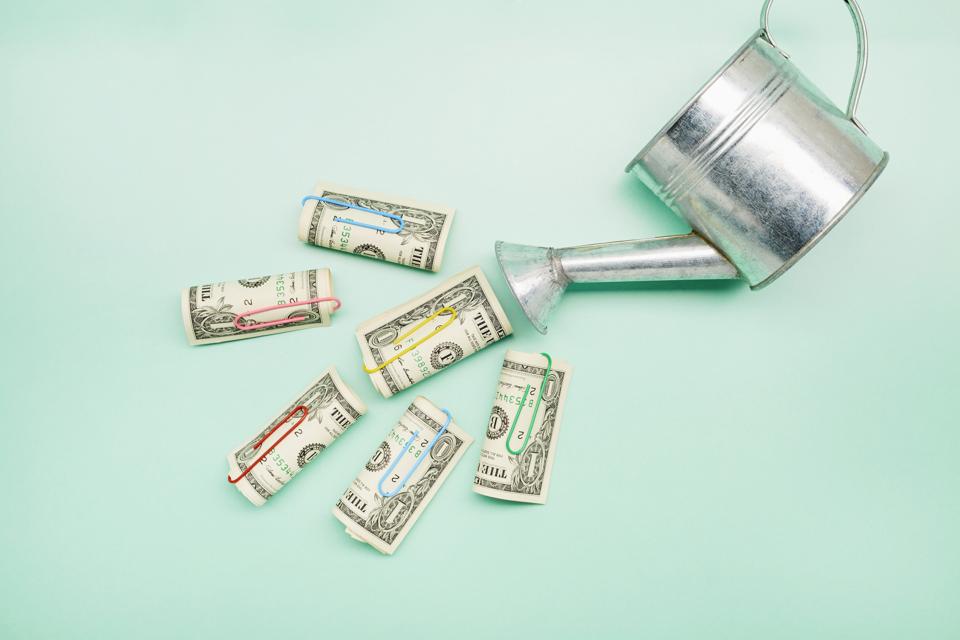 Watering can and American Dollar banknotes on turquoise background