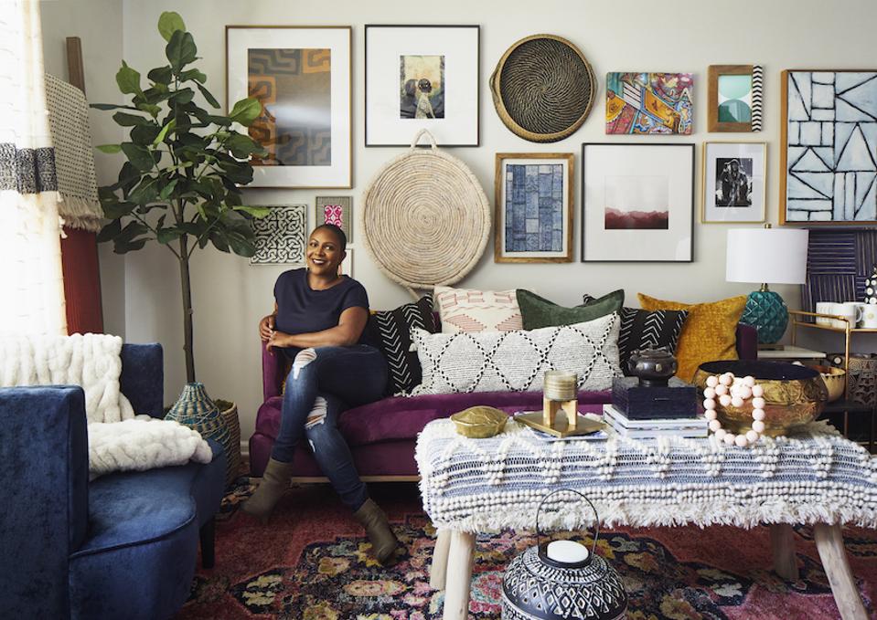 A woman sits in front of a living room gallery wall