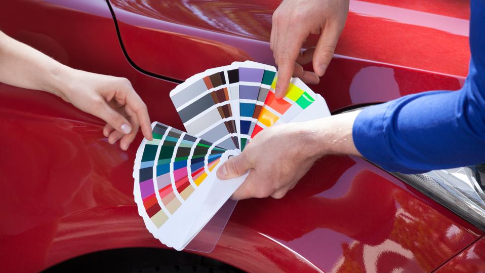 Mechanic Showing Color Samples To Customer Against Car