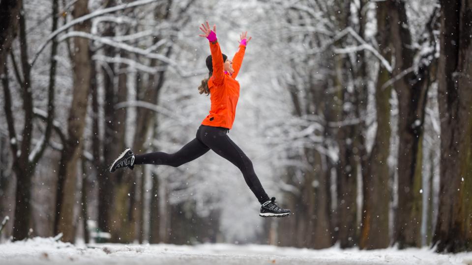 Jump! - side view woman jumping for joy in winter