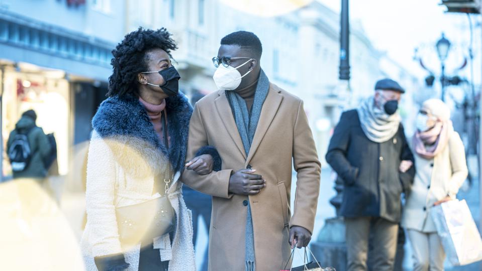 Young couple at Christmas shopping, COVID-19 pandemic. They wearing a protective mask to protect from corona virus COVID-19