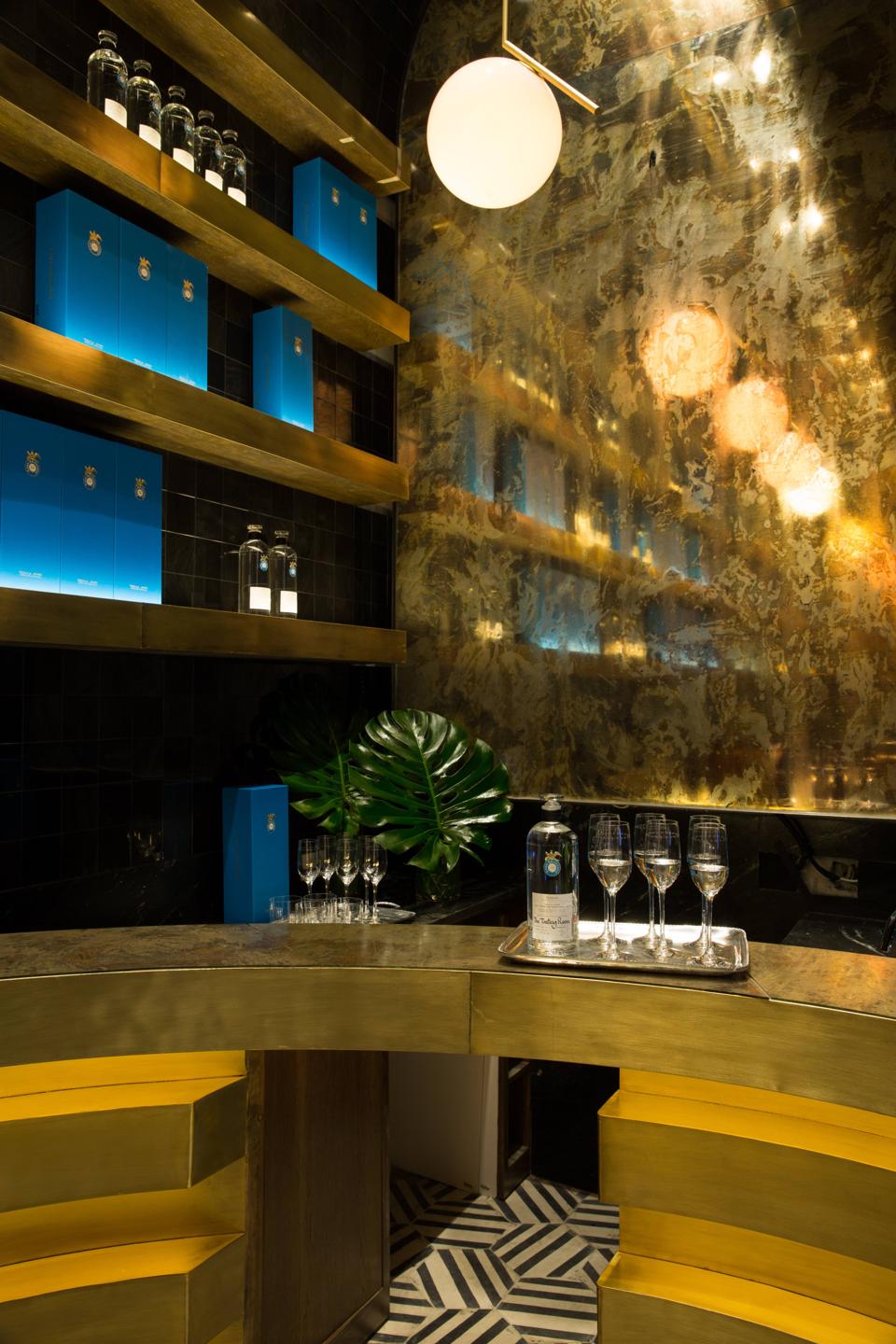 The tasting room, with a gold bar, mirrored wall and an opposing obsidian-tiled wall.