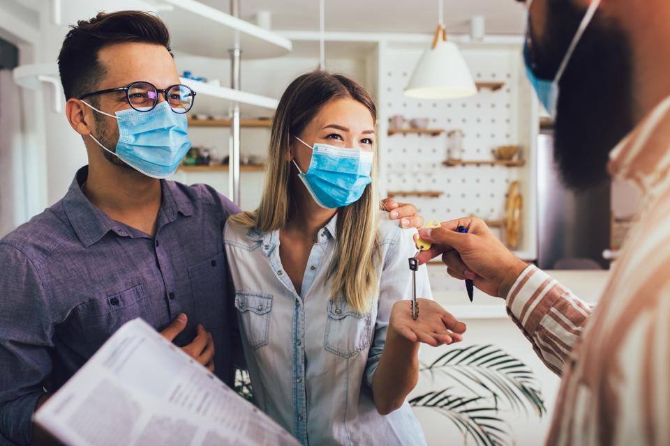 Couple in protective masks with male real estate agent.