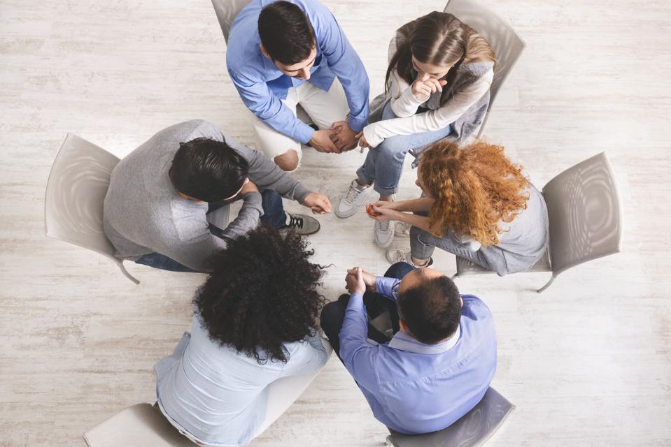 Group of people sitting in circle, dicussing problems during therapy session
