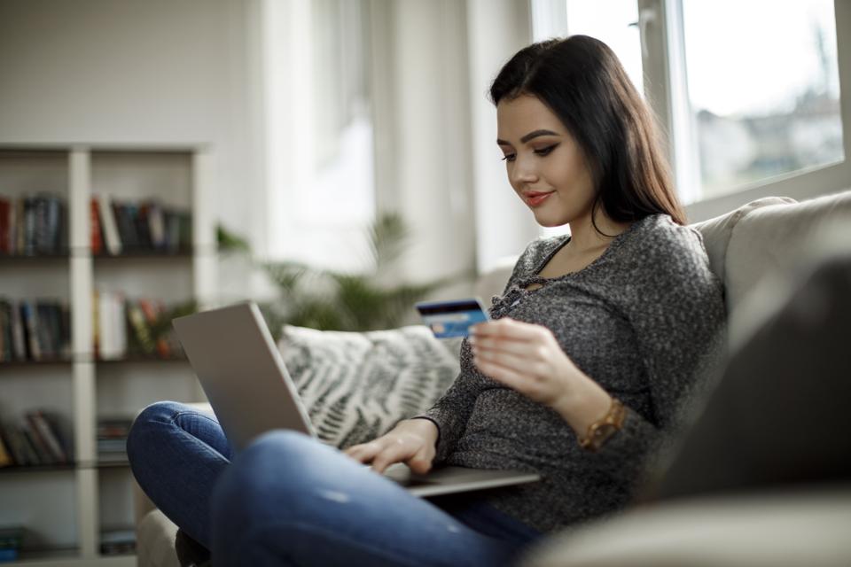 Smiling young woman using laptop for online shopping