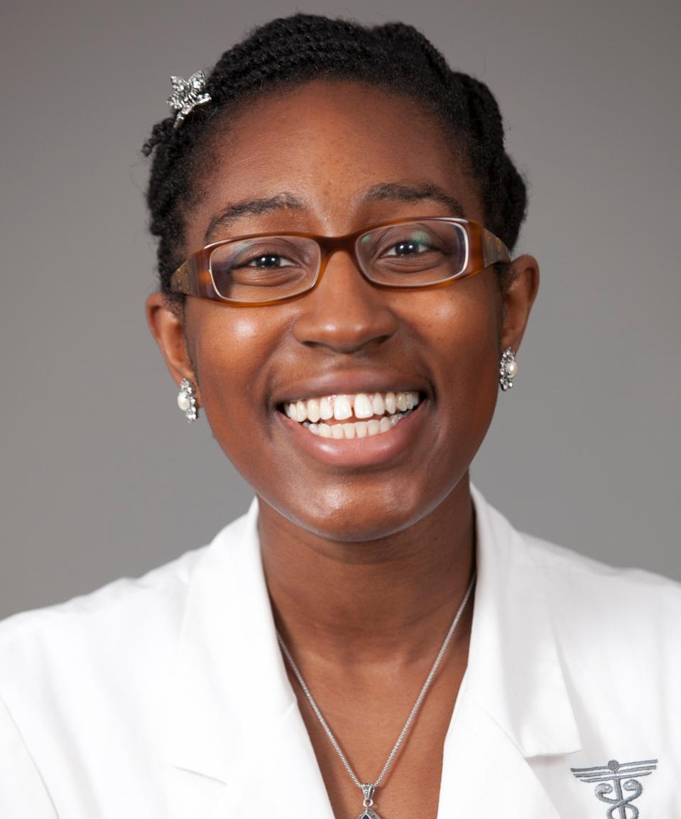 Une femme noire dans des verres et une blouse blanche à la recherche dans la caméra en souriant