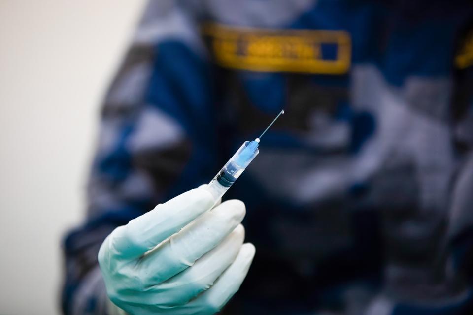 A health worker holds up a syringe with the Oxford-...