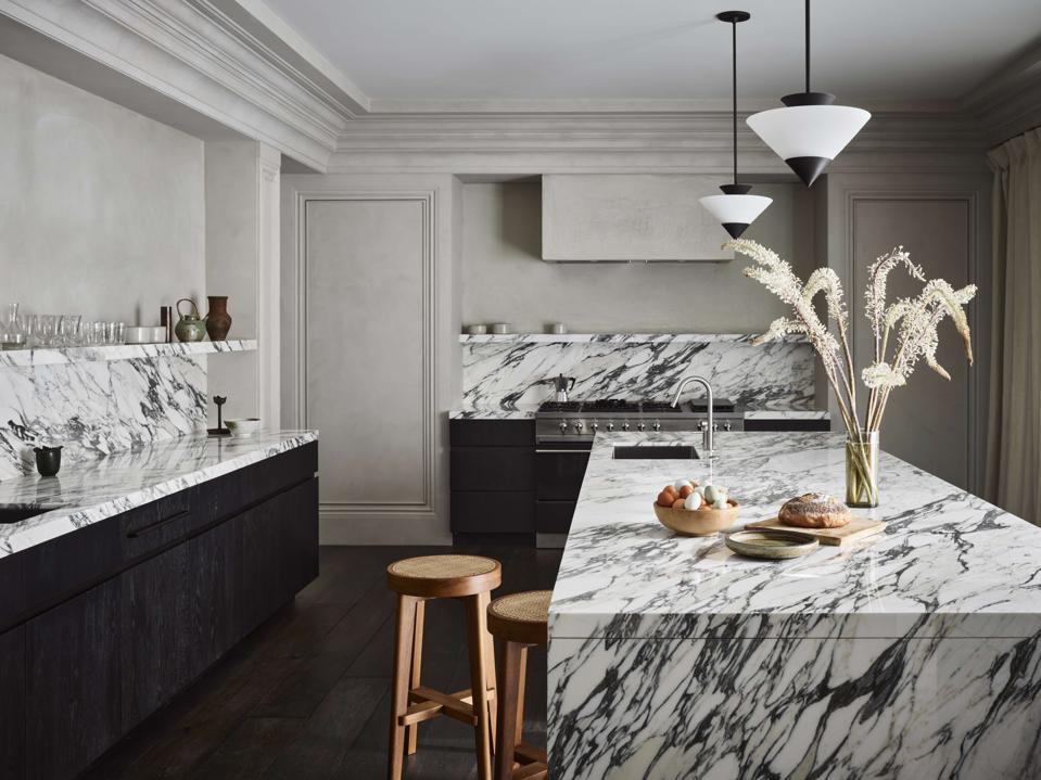 The kitchen, with a large marble island in the center and marble backsplashes and shelving.