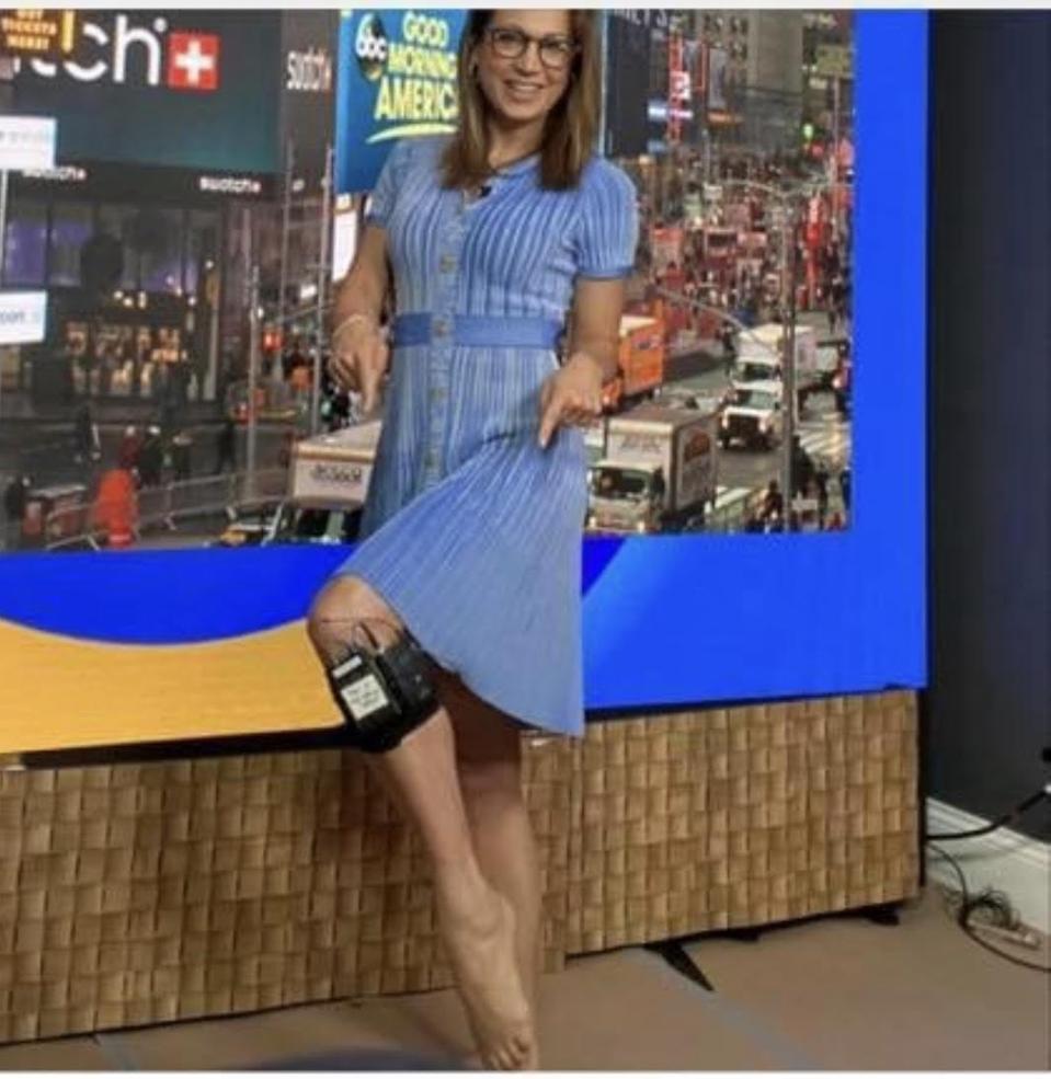 A white woman with glasses and a blue dress poses wearing the AHA wrap.