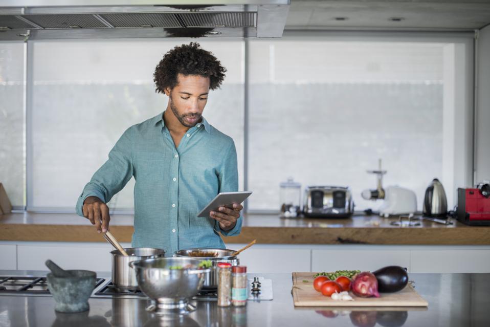 Man cooking reading a tablet while cooking