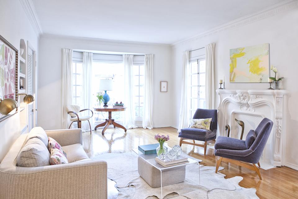 A living room white fireplace and wood floors.