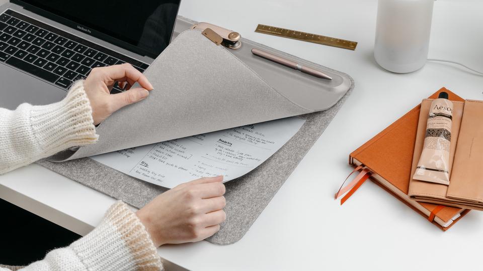 woman lifting corner of desk mat to reveal papers