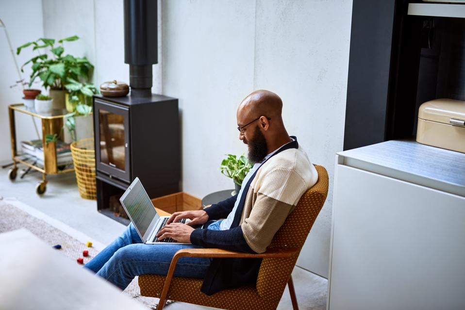 Man with beard using laptop at home on retro chair