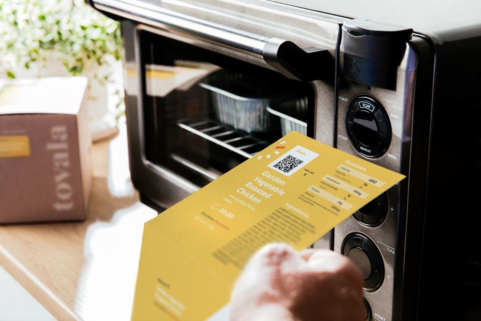 A customer scans a recipe on Tovala's smart-oven, which is programmed to cook the meal to pre-programmed specifications.