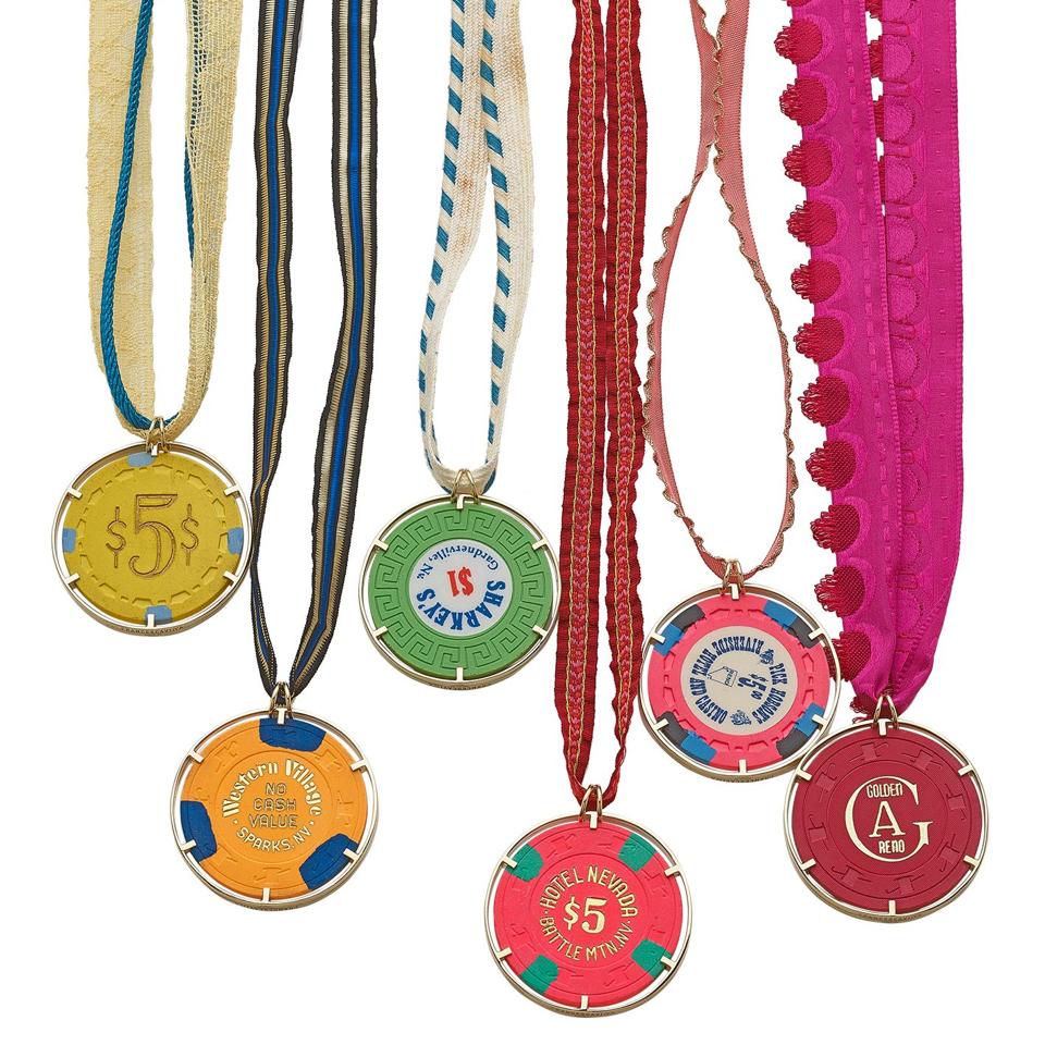 Casino gambling chip pendant necklaces set in 18-karat gold hang on colorful cloth cords.