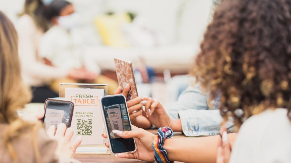 Group of female colleagues use online ordering at patio restaurant