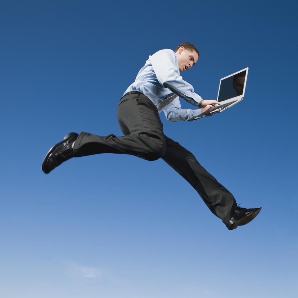 African businessman typing on laptop in mid-air