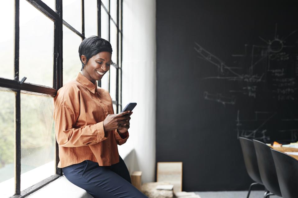 Smiling entrepreneur using phone in office meeting