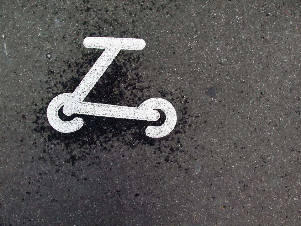 The logo of a painted scooter on an asphalt street in Paris