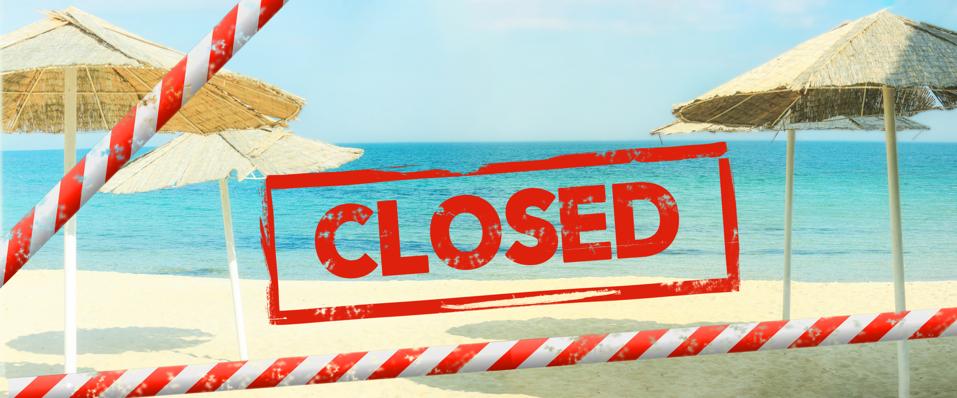 Red inscription ″closed″ on a blurred background of a deserted beach. Beach is closed with a  red barrier tape. Concept: vacation canceled due Covid-19, resort closing due to quarantine
