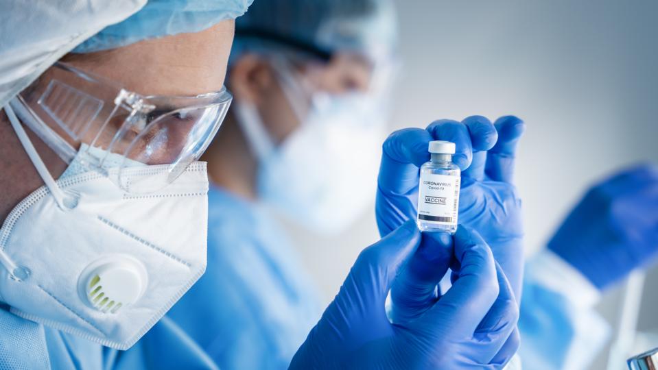 coronavirus covid-19 vaccine bottle in hands of pharmacuetical and vaccine research scientist in laboratory, coronavirus covid-19 vaccine development