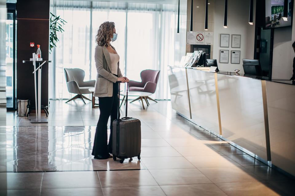 Beautiful woman with medical mask arriving in hotel