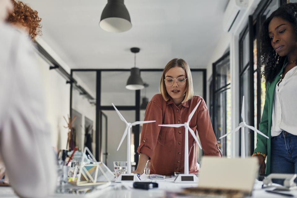 Businesswomen having a meeting in office with wind turbine models on table