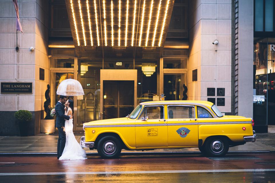 A bride and groom stand beside a vintage taxi at the Langham, New York, hotel