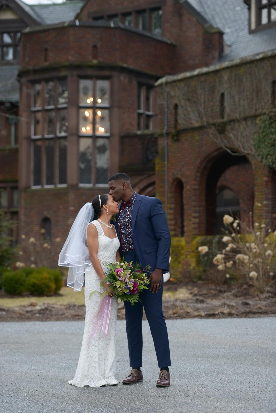 A bride and groom stand in front of the redbrick Blantyre hotel in Massachusetts