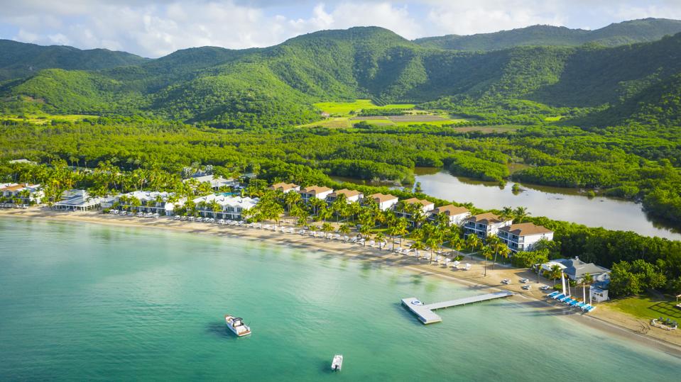 Carlisle Bay in Antigua is seen from above with the sea in front and green hills behind
