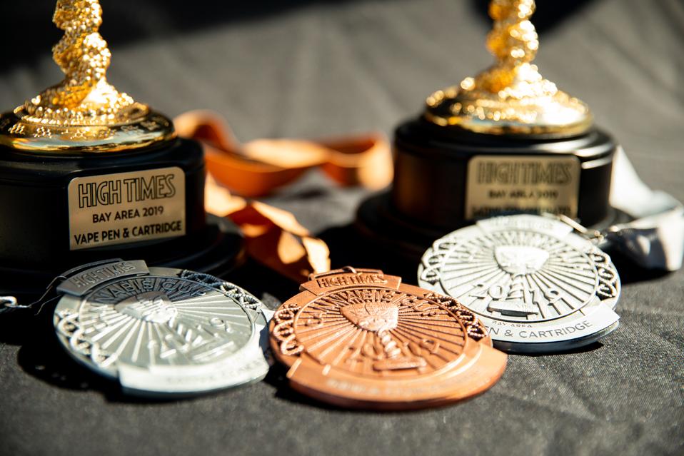 A closeup of High Times Cannabis Cup trophies and medals.